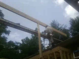Carpenter setting a ridge beam over a new addition frame — Ice Dam Removal by Roofing Brothers in Tuscaloosa