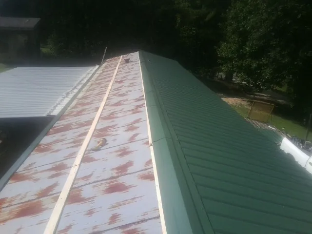Old rusted panels beside newly installed green metal roofing — Wind Damage Roof Repair by Roofing Brothers in Tuscaloosa