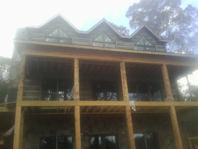 Dormers and porch framing on a large log home under construction — Roof Coating work by our crew in Tuscaloosa