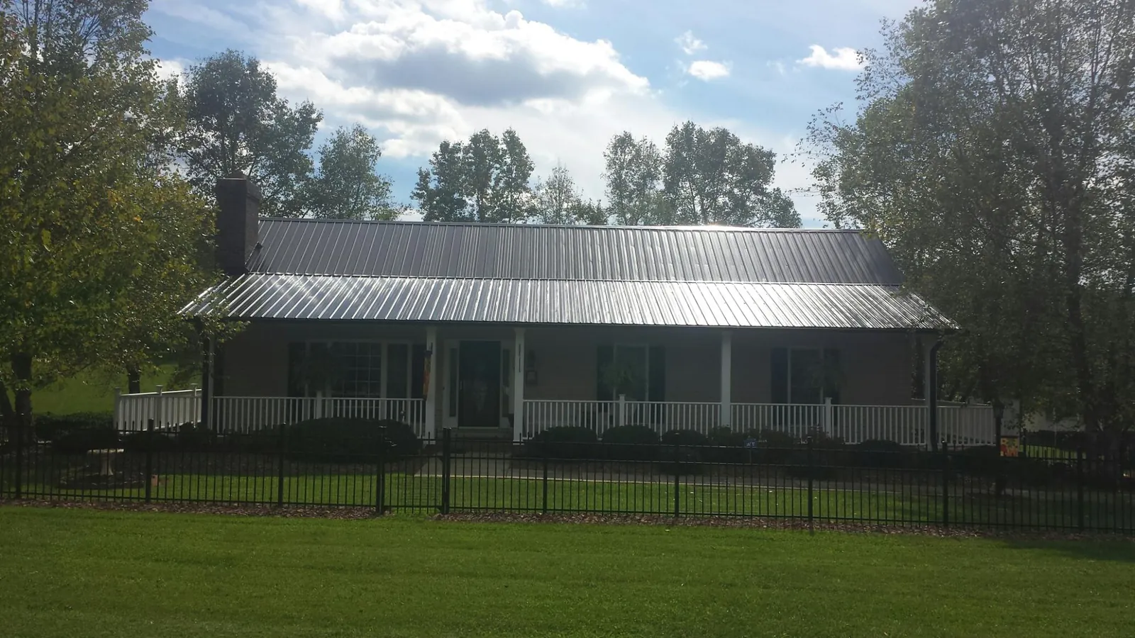 Gray metal roof on a brick ranch with a full width front porch — Gutter Guard Installation work by our crew in Tuscaloosa