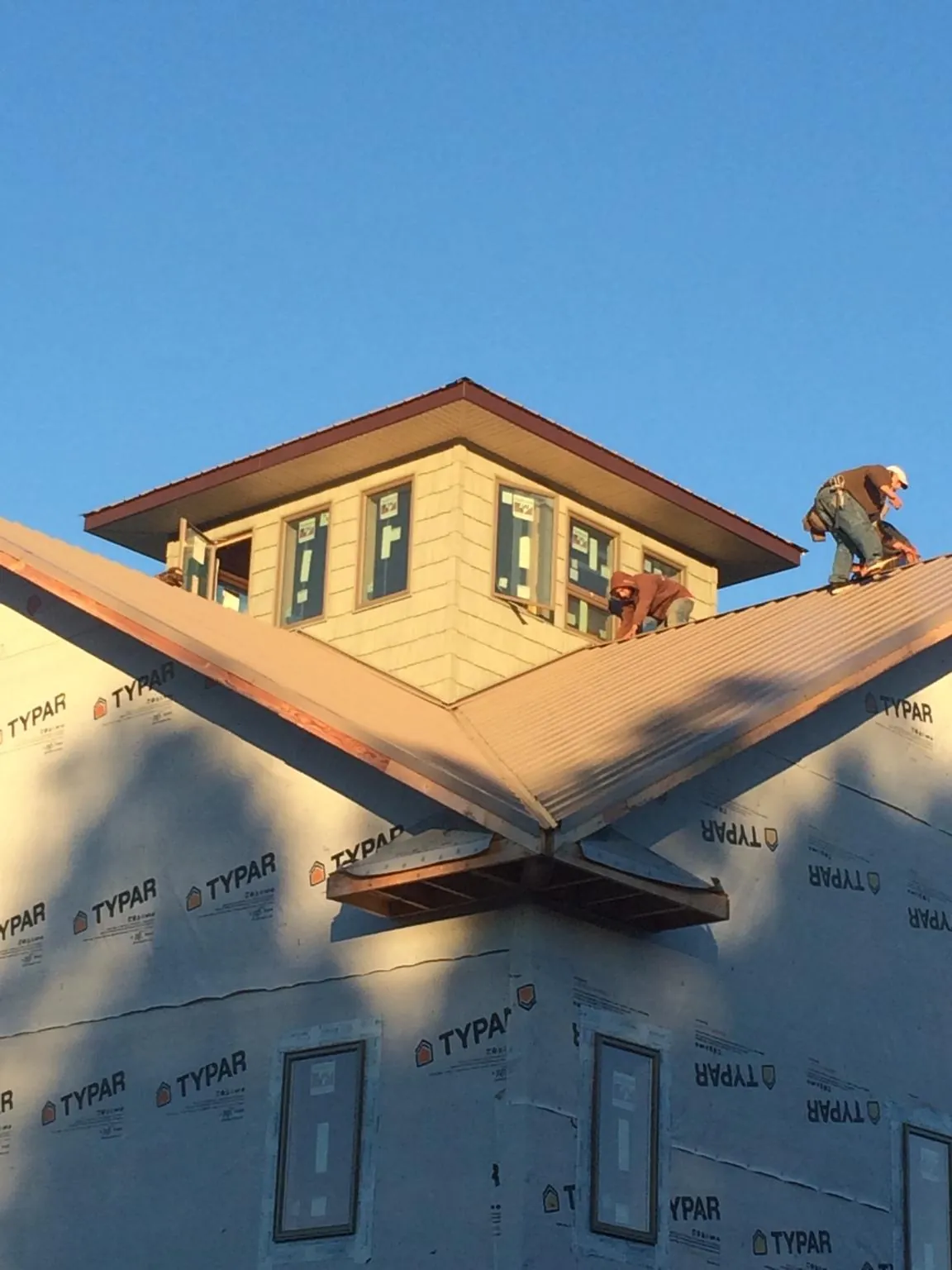 Roofers working around a rooftop cupola on a new metal roof at sunset — Roof Waterproofing in Tuscaloosa by Roofing Brothers